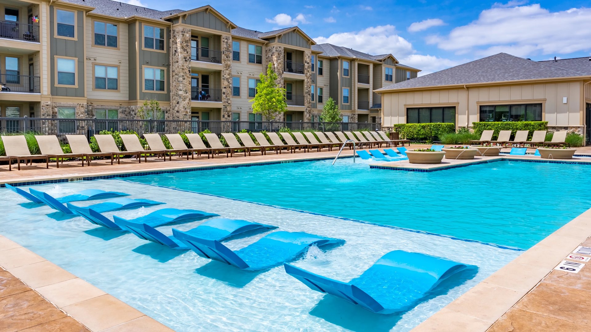 Resort-style pool with in-water loungers and sundeck at The Crawford at Grand Morton