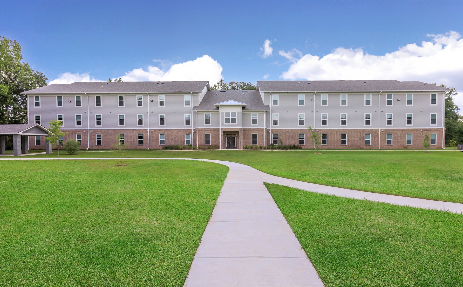 a large brick building with green grass