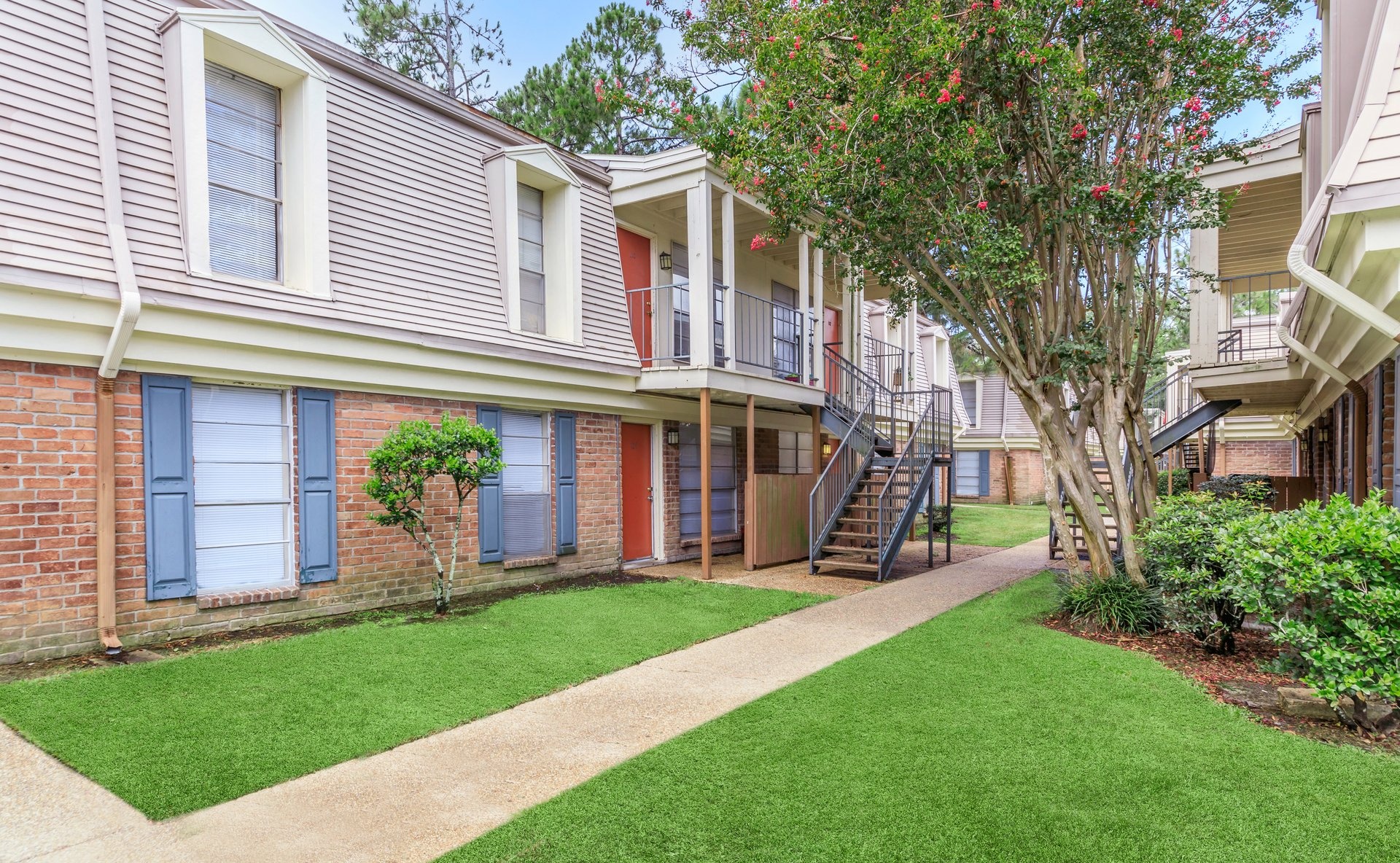 a large brick building with grass in front of a house